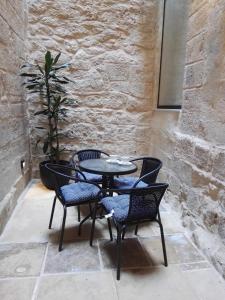 a table and four chairs sitting next to a stone wall at Vallettastay Casa Zoe in Valletta