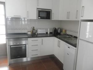 a kitchen with white cabinets and stainless steel appliances at Casa Barrela II in Tavira