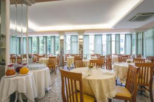a dining room with tables and chairs and windows at Hotel del Falco in Cervia