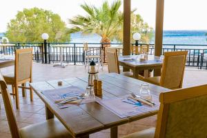 a wooden table and chairs on a patio with the ocean at Triton Authentic Cretan Hotel in Tsoutsouros