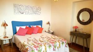 a bedroom with a bed with red pillows and a mirror at La Casa de la Abuela in Ponta do Sol