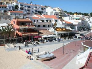 a group of people walking on a beach with buildings at Beach Apartment Carvoeiro in Carvoeiro