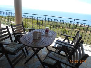 d'une table et de chaises en bois sur un balcon donnant sur l'océan. dans l'établissement Regina apartments Simotata Sissia, à Lourdhata