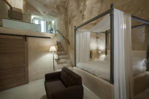 馬泰拉的住宿－彼得拉艾露酒店，一间卧室配有一张天蓬床和一把椅子