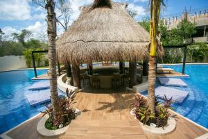 a resort with a swimming pool and a hut with palm trees at Paramar Terra in Tulum