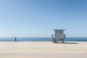 a person standing on a beach with a lifeguard tower at Days Inn by Wyndham Corpus Christi Beach in Corpus Christi