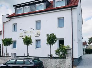 ein weißes Gebäude mit einem davor geparkt in der Unterkunft Hotel Tommasi in Mörfelden-Walldorf