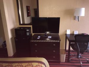 Habitación de hotel con escritorio y TV de pantalla plana. en Days Inn by Wyndham Corpus Christi Beach, en Corpus Christi