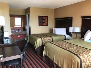 Habitación de hotel con 2 camas y escritorio en Days Inn by Wyndham Corpus Christi Beach, en Corpus Christi