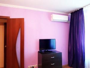 モスクワにあるКвартира посуточно метро Пролетарскаяのピンクの壁のドレッサーにテレビが備わる客室です。