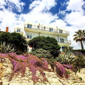 a white building with purple flowers in front of it at Villa Grachira in Fertilia