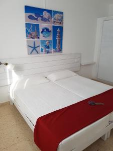 a bedroom with a white bed with a red blanket at Viviendas Es Carritx in La Mola