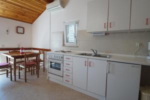 a kitchen with white cabinets and a table and a sink at Guest house Šuda in Lumbarda