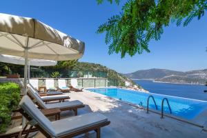a pool with lounge chairs and an umbrella and the ocean at Villa Kiki in Kalkan