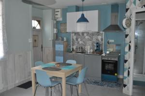 a kitchen with a wooden table and blue walls at Le studio d'Ahynoa in Lauzun