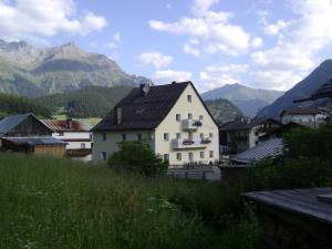 a white house in a village with mountains in the background at Apart Hofer in Nauders