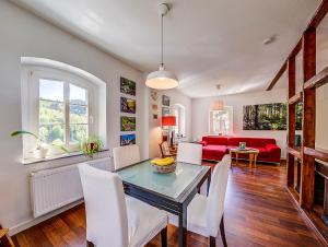 ein Wohnzimmer mit einem Tisch, Stühlen und einem roten Sofa in der Unterkunft Kutscherhaus Monschau in Monschau