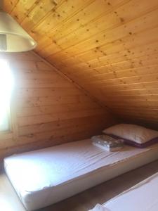 a bed in a cabin with a wooden ceiling at Domki Międzyzdroje in Międzyzdroje