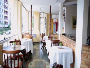 un restaurante con mesas y sillas blancas y ventanas en Pousada Bariloche, en Teresópolis