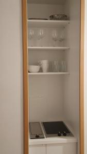 a kitchen shelf with cups and dishes on it at Studio Concept Apartment in Zagreb