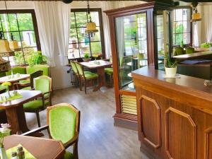 a restaurant with green chairs and tables and windows at Landhaus Brockenblick in Hohegeiß