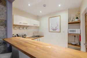 cocina con armarios blancos y encimera de madera en Rose Apartment, en Edimburgo