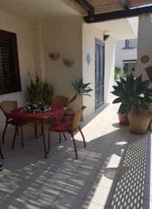 un patio con tavolo, sedie e piante in vaso di Guest House Adele a Marina di Ragusa