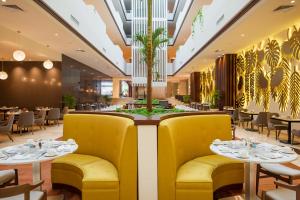 a restaurant with yellow chairs and tables and a palm tree at The Reef 28 Hotel & Spa - Luxury Adults Only - All Suites - With Optional All Inclusive in Playa del Carmen