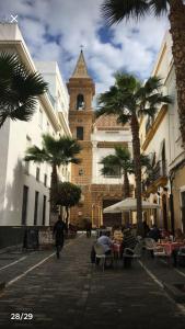 カディスにあるCasa de Corralónの時計塔とヤシの木がある建物