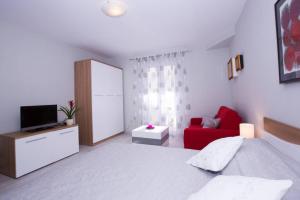 1 dormitorio con 1 cama y 1 sofá rojo en Apartments Daisy, en Dubrovnik