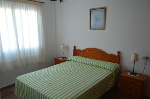 1 dormitorio con 1 cama con manta de rayas verde y blanca en Hnos Navarrete, en Fuengirola