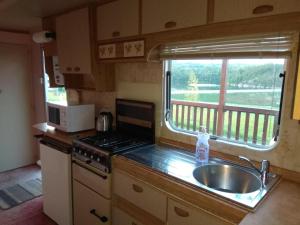 a kitchen with a sink and a stove and a window at Mobilheim Vyhlídka Camp Výrovice in Výrovice