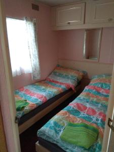 two beds in a small room with a window at Mobilheim Vyhlídka Camp Výrovice in Výrovice