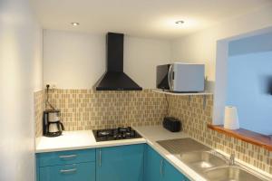 a kitchen with blue cabinets and a sink and a microwave at Villa Yona in Sainte-Anne