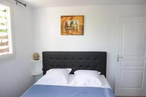 a bed with a black headboard in a white bedroom at Villa Yona in Sainte-Anne