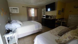 a bedroom with two beds and a desk with a microwave at Villa Brasil Motel in Los Angeles