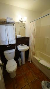 a bathroom with a toilet and a sink and a tub at Villa Brasil Motel in Los Angeles