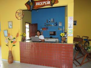 une femme assise au comptoir avec un ordinateur portable dans l'établissement Pousada Reflexo das Águas, à Santo Amaro