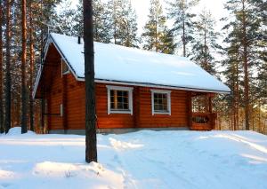 a log cabin with snow on the roof in the woods at Kettu Holl Cottage in Taipalsaari