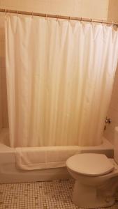 a bathroom with a white shower curtain and a toilet at HWY6HOTEL in Oak Point