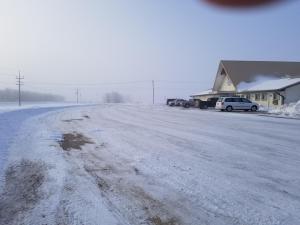 a snow covered road with cars parked next to a building at HWY6HOTEL in Oak Point