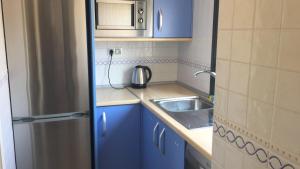 una pequeña cocina con armarios azules y fregadero en Apartamento con fantásticas vistas al mar, en Benidorm