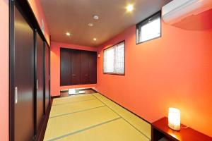an empty hallway with orange walls and a carpeted floor at Guest House Ochakare in Kanazawa