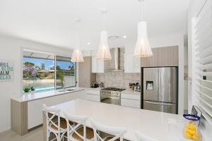 a white kitchen with a large white table and chairs at Sandy Cove in Gold Coast