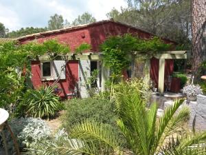 una casa roja y blanca con plantas alrededor en Les Gîtes Les Mayombes, en Roquebrune-sur-Argens
