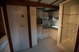 eine Küche mit weißen Schränken und einer Glastür in der Unterkunft Petite Cahute in Soultzmatt