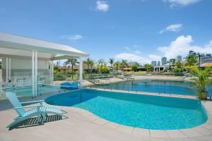 a swimming pool with two chairs next to a house at Sandy Cove in Gold Coast