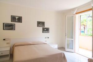a white bedroom with a bed and a window at Residence Hotel Villa Mare in Portoferraio