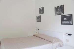 uma cama num quarto com fotografias na parede em Residence Hotel Villa Mare em Portoferraio