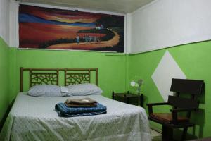 a green bedroom with a bed and a painting on the wall at Hostal del Este Santa Fe in San José